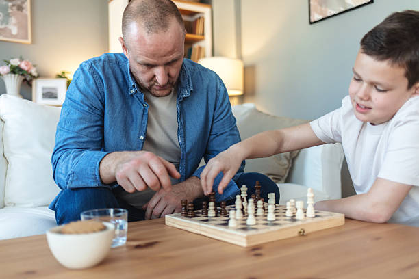 istock Father and son play chess together at home. 2250705340