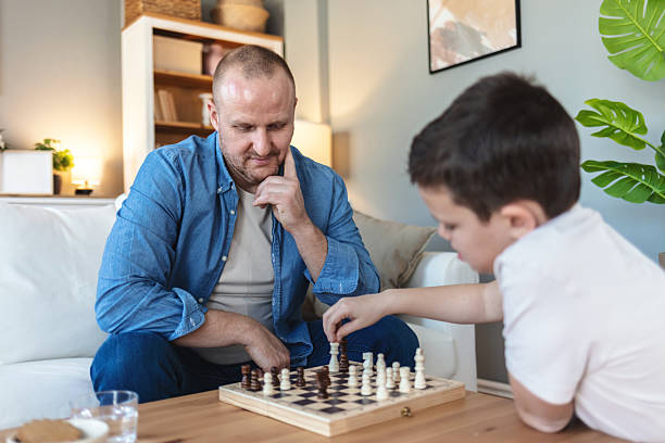 istock Playing, hands and father with kid for chess in home for learning, development or bonding. Teaching, competition and dad with boy child for board game with checkmate for problem solving skills. 2250705362