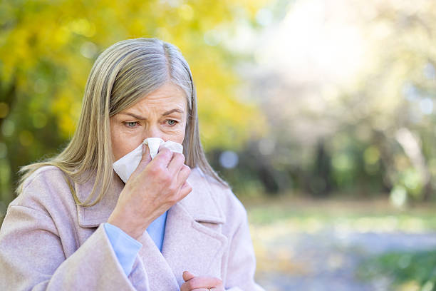 istock Senior woman blowing nose using tissue outdoors 2250708821