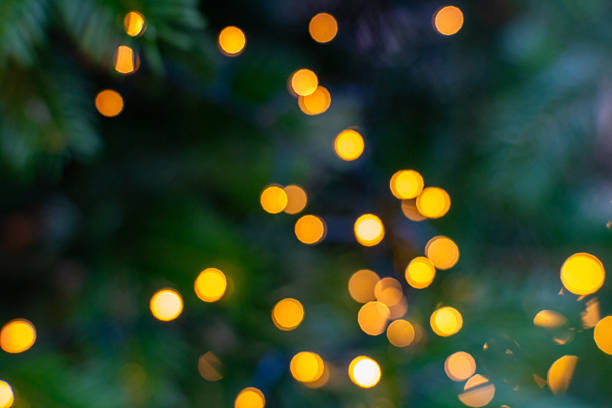 istock Soft golden bokeh lights glowing on a blurred evergreen background 2250709436