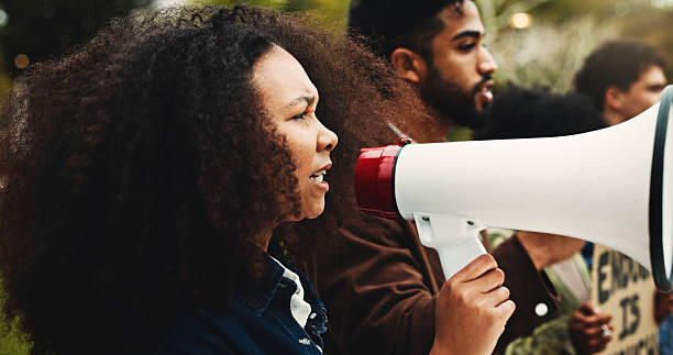 istock Climate change, protest and woman with megaphone, environment and awareness with ecology. Outdoor, people and crowd with bullhorn, group activism or screaming with global warming, unity or solidarity 2250715922