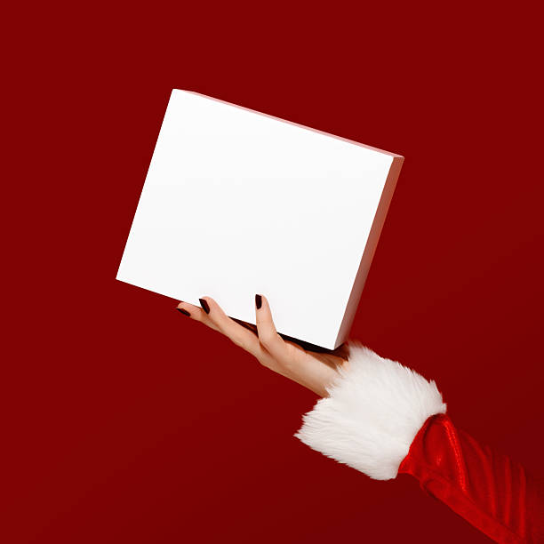 istock Santa-style hand holding blank white gift box on red background. Perfect for packaging mockups 2250723016