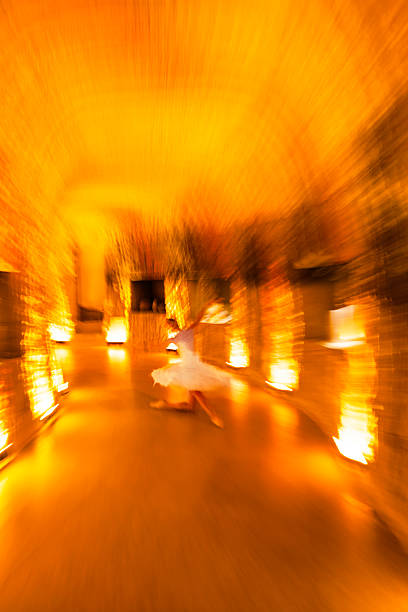 A dreamy, abstract motion-blur photograph of a ballet dancer performing in a warm, golden-lit underground space. The dynamic zoom effect creates a sense of energy, fluid movement and artistic expression. Ideal for themes of creativity, performing arts, dance, motion, and atmospheric interiors.