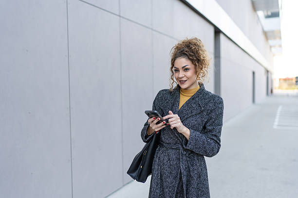 istock Young woman walking outdoors and using smartphone 2250728737