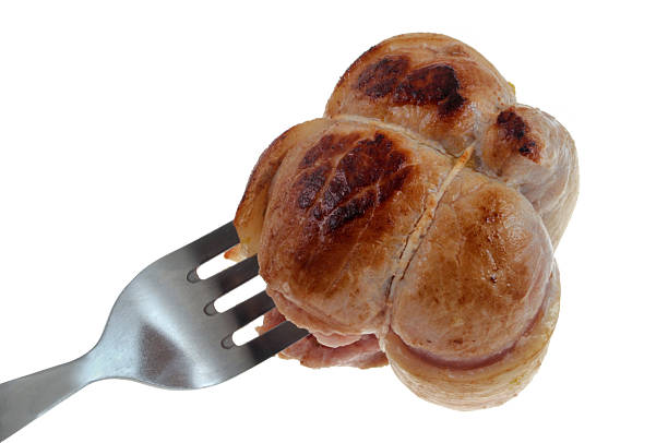 Closeup of a cooked veal paupiette skewered on a fork, isolated on a white background
