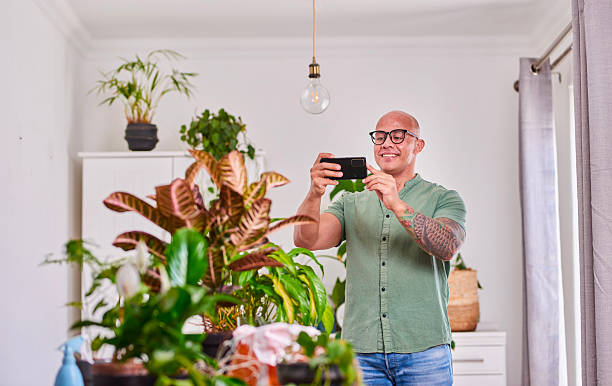 istock Happy Man With Glasses Capturing Indoor Plant Life In A Bright Home Setting 2250736794