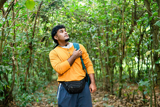 Young adult man exploring lush green forest with a backpack, enjoying the outdoors