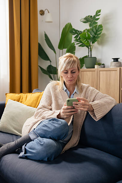 istock Woman relaxing at home using smartphone on couch 2250743103