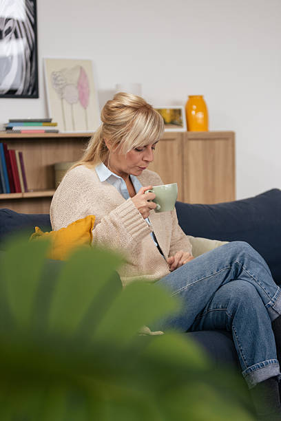 istock Woman relaxing on sofa drinking hot beverage 2250743110