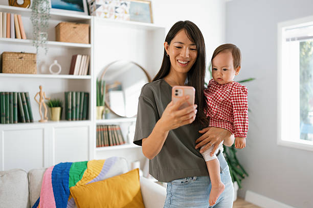 istock Mom Holding Toddler While Texting on Phone 2250746886
