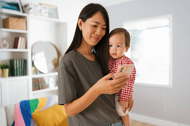 istock Mom Holding Toddler While Texting on Phone 2250746941