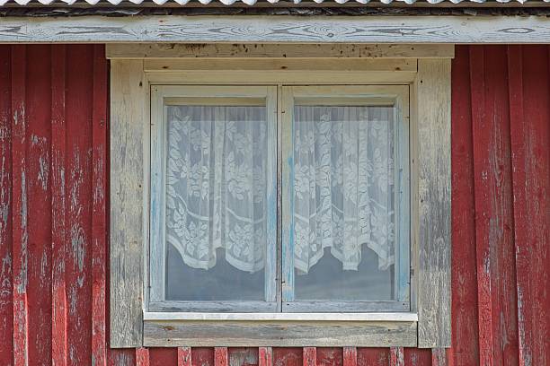 Rustic window view from seaside cabin, the building has a traditional red wood siding and a white window frame in summer, Vöyri, Finland.