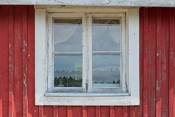 Rustic window view from seaside cabin, the building has a traditional red wood siding and a white window frame in summer, Vöyri, Finland.