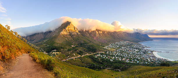Table Mountain above the ocean at sunset, under a sky of colourful clouds, as seen from Bloubergstrand in Cape Town, South Africa