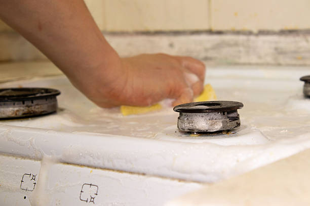 istock Hand Scrubbing a White Gas Stove Cooktop with a Soapy Sponge 2250752590