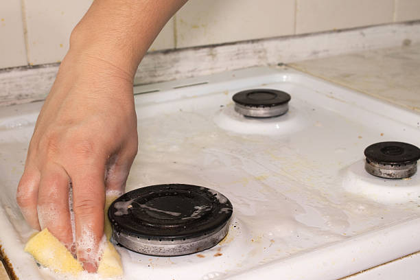 istock Hand Scrubbing a White Gas Stove Cooktop with a Soapy Sponge 2250752631