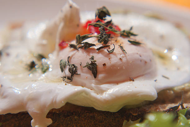 A poached egg sits atop toasted bread, garnished with herbs and spices.