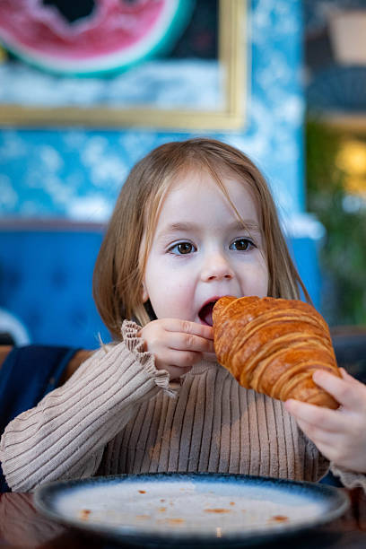 Child enjoying breakfast croissant at a cafe