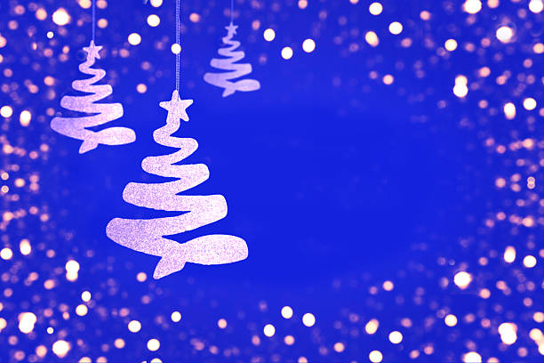 Glittering hanging trees set against a blue backdrop with soft, warm bokeh lights for a festive, magical mood.