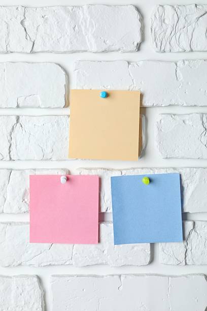 istock Colored paper stickers attached with pushpin on a white brick wall 2250764723
