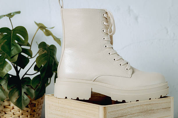istock One left, cream-colored, rough-soled boot on a wooden box on the floor near a cement wall. 2250766964