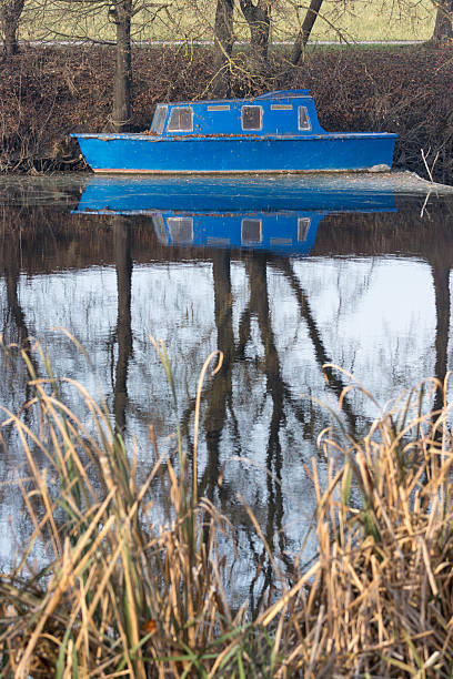istock Blue Boat Reflected in a Calm River Surrounded by Natural Scenery 2250767026