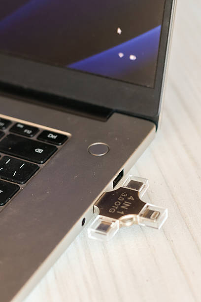 istock Silver laptop with multi-port USB drive plugged into side port on wooden surface 2250769938