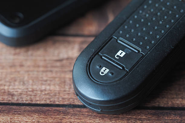 Detailed view of a black remote control resting on wooden surface.