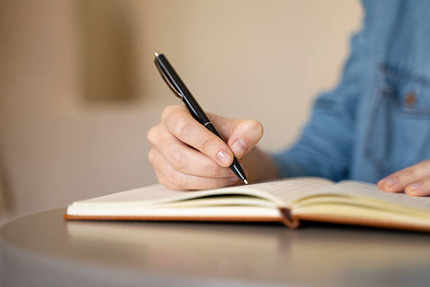 istock Close up of a woman's hand writing in notebook with a pen. 2250773181