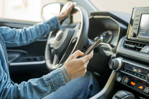 istock Close up of distracted woman's hands using mobile phone while driving a car. 2250773197