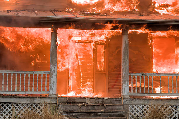 Blackened shell of a house after a fire, windows busted out and roof damaged