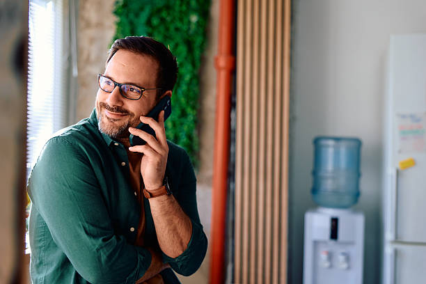 istock Happy man in glasses talking on mobile phone at office 2250776793