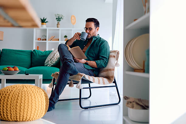 istock Man relaxing at home reading book drinking coffee 2250777558