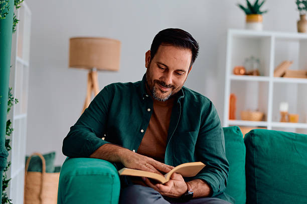 istock Man relaxing on sofa reading book at home 2250777903