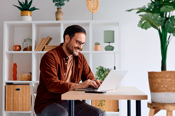 istock Smiling man working on laptop from home office 2250778625