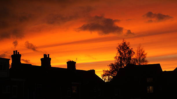 stunning orange sky with clouds at sundown and homes in Silhouette
