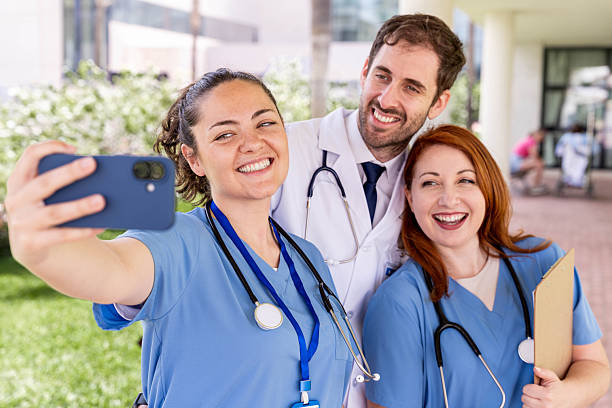 istock Three smiling healthcare workers a doctor and two nurses taking a selfie, enjoying teamwork and camaraderie outdoors 2250785552