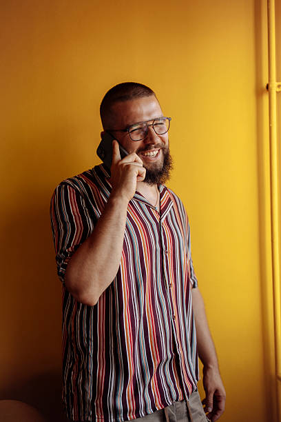 istock Man on the phone smiling beside a yellow wall 2250786559
