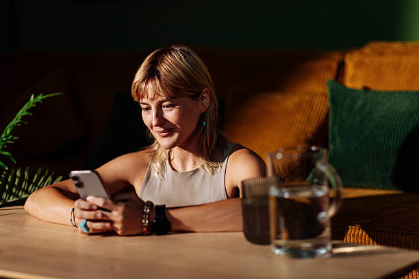 istock Woman relaxing at cafe table using smartphone 2250786637
