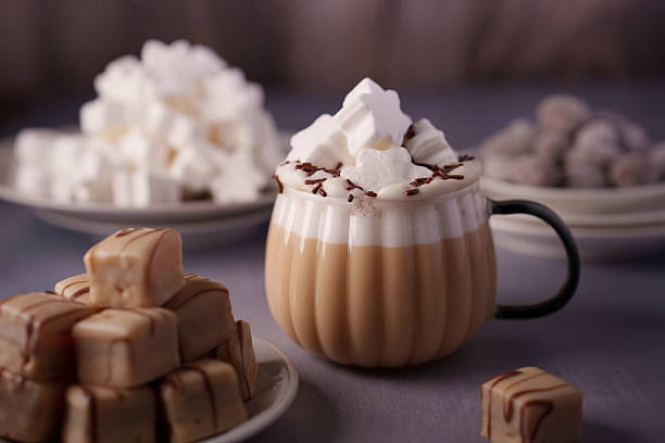 istock cozy scene featuring a creamy latte topped with star-shaped marshmallows and chocolate shavings, set amidst plates of assorted sweets, evoking warmth and indulgence on a soft, muted background 2250787981