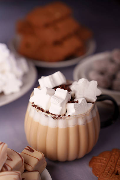 istock a cozy setting featuring a creamy beverage topped with marshmallows and chocolate sprinkles, surrounded by an assortment of sweet treats and pastries on a soft, muted background, bakery, plateware 2250788010