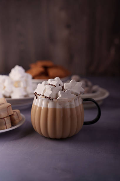 istock cozy hot chocolate with star-shaped marshmallows in a textured mug surrounded by assorted confections on a soft grey surface and a warm wooden background, treat, afternoon, relaxation, served 2250788013