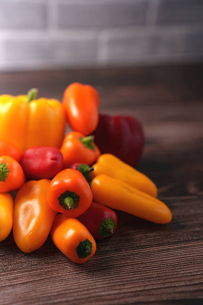 istock vibrant array of assorted peppers on wooden table with soft brick wall backdrop, showcasing a colorful and fresh presentation of yellow, orange, and red bell peppers, autumn, variety, decorative 2250788192