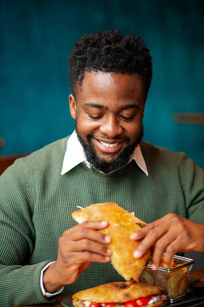 istock Young Black man holding sandwich in restaurant 2250789546