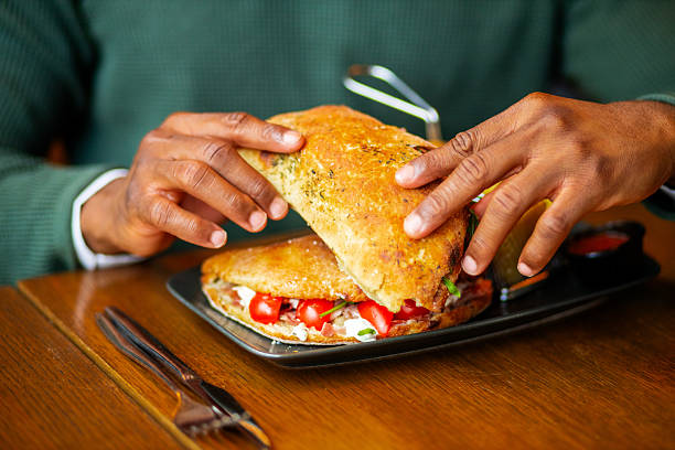 A cropped image of a woman's hand holding a toasted bread with scrambled eggs and katsuobushi on top, as she enjoys a healthy breakfast in the morning