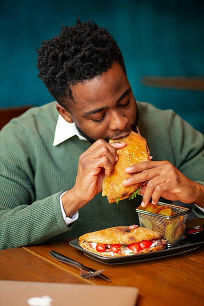 istock Young Black man taking first bite of sandwich 2250789562