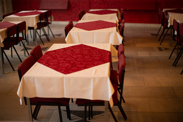 Set Dining Table With Red Centerpiece And White Linen, Four Chairs Arranged Symmetrically On Tiled Floor Close Framing Emphasizes Pattern, Color