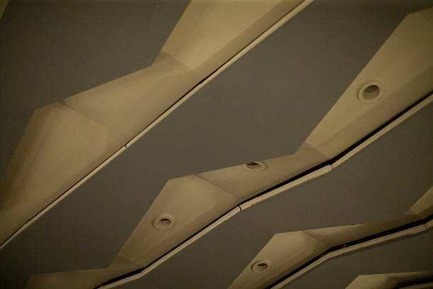 Angled Ceiling Panels Form Repeating Pattern. CloseUp View Of Ceiling Geometry Showing Overlapping Panels, Casting Alternating Light And Shadow