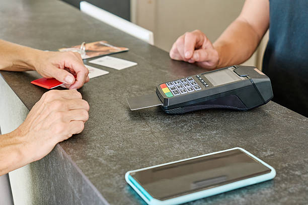 istock Unrecognizable woman completing a payment with a credit card at reception desk using a POS terminal for transaction 2250793818