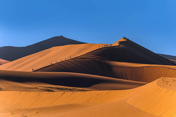 istock People Trekking Dune Ridge Under Blue Sky 2250796398